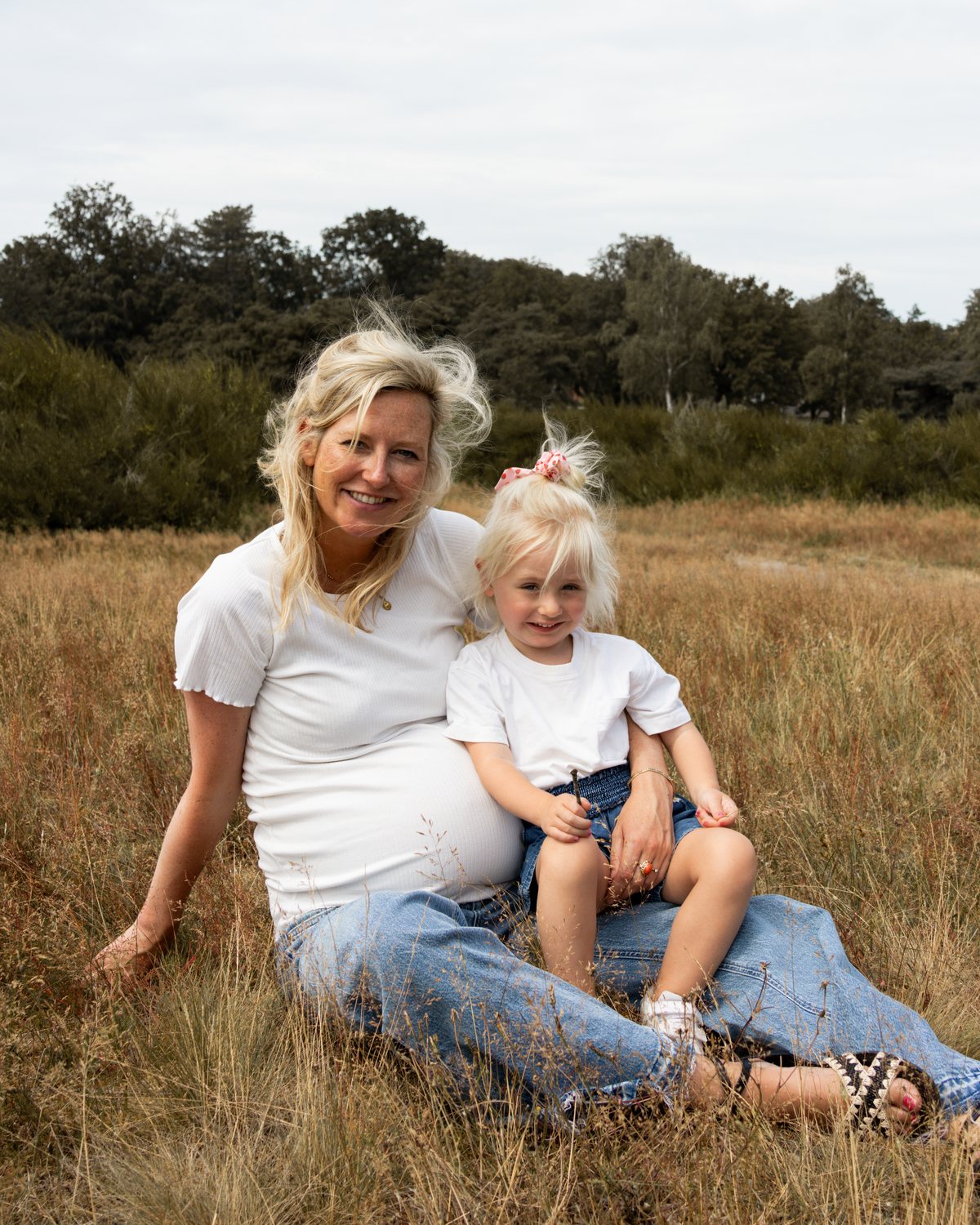 Zwangere moeder met haar dochtertje in het gras